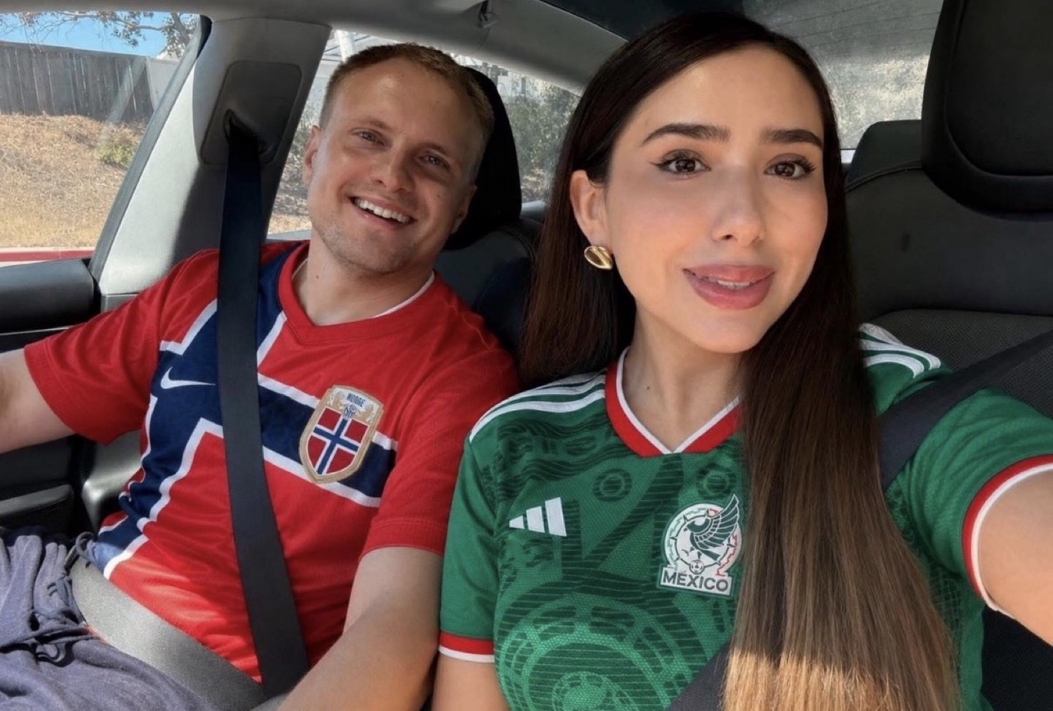 A recent photo in the United States of two people in a car wearing football shirts.
